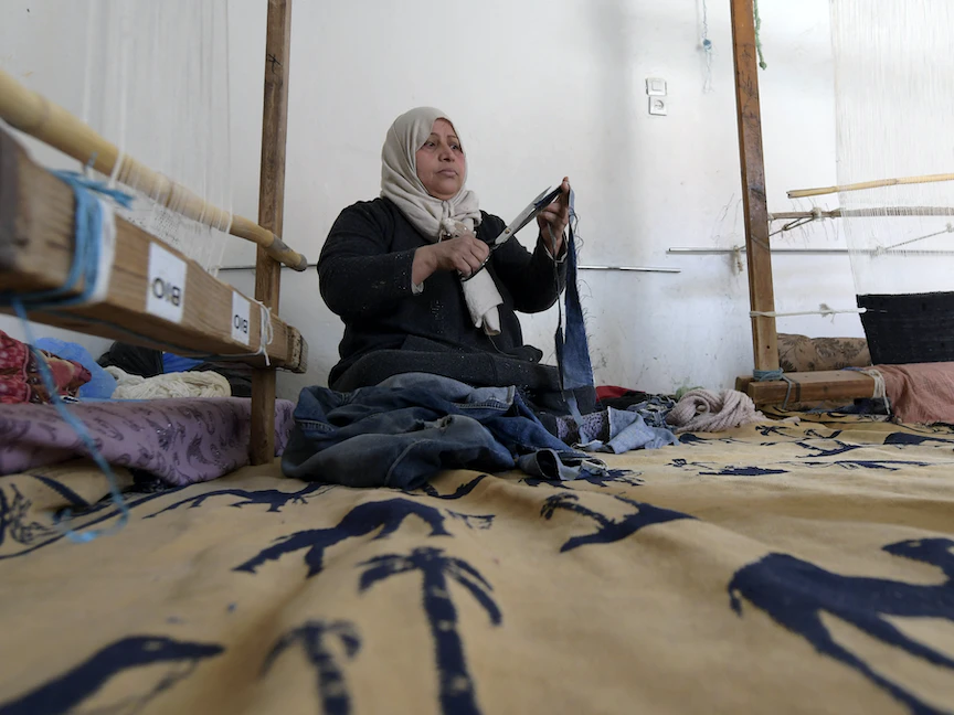 نجاة أثناء عملها في مشروع اجتماعي لإعادة تدوير الملابس وتحويلها إلى سجاد، نفطة، جنوب غرب تونس. - AFP