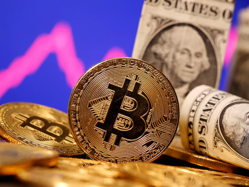 عملة "بيتكوين" الرقمية وفي الخلفية أوراق نقدية من فئة الدولار- 8 يناير 2021 - REUTERS