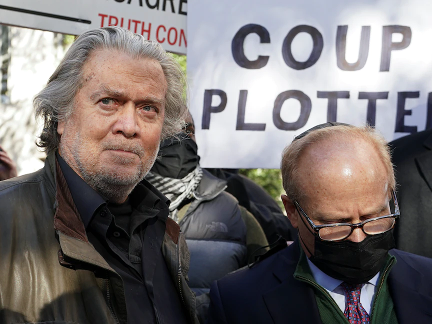 ستيف بانون مستشار الرئيس الأميركي السابق دونالد ترمب يغادر المحكمة في واشنطن وفي الخلف شخص يرفع لافتة كتب عليها "مُخطط الانقلاب"- 15 نوفمبر 2021 - REUTERS
