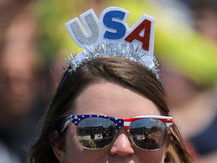 أميركية ترتدي نظارة عليها علم الولايات المتحدة خلال مسابقة ناثان الشهيرة لأكل النقانق في حديقة ميمونيدس في مدينة نيويورك - 4 يوليو 2021 - REUTERS