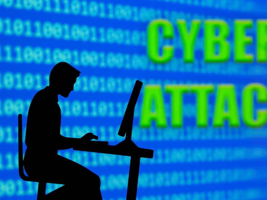 صورة توضيحية لرجل يعمل على الكمبيوتر بجانب جملة "هجوم إلكتروني" - REUTERS