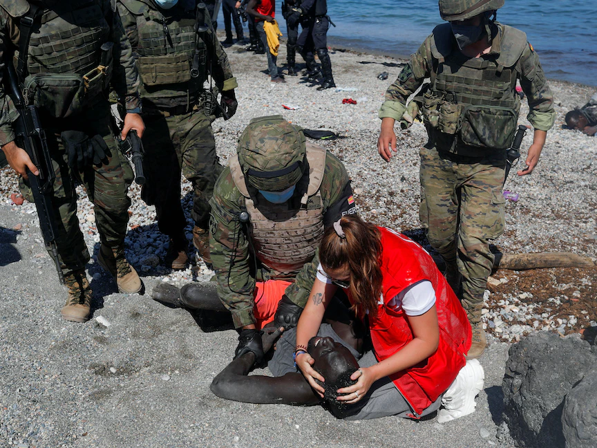 عضوة بالصليب الأحمر الإسباني تسعف مهاجراً غير شرعي من منطقة الصحراء على شاطئ التراجال في سبتة - 18 مايو 2021 - REUTERS