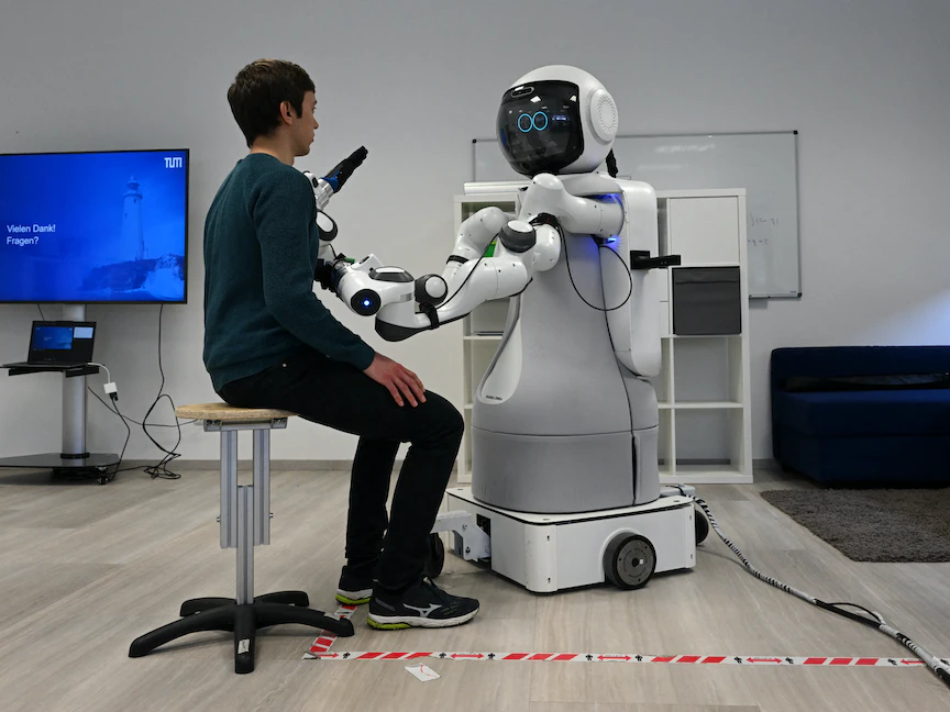 موظف يجلس أمام الروبوت جارمي في مختبر مركز الأبحاث جيرياترونيكس التابع لجامعة ميونيخ التقنية في جارمش بارتنكيرشن بجنوب ألمانيا. 6 مارس 2023 - AFP