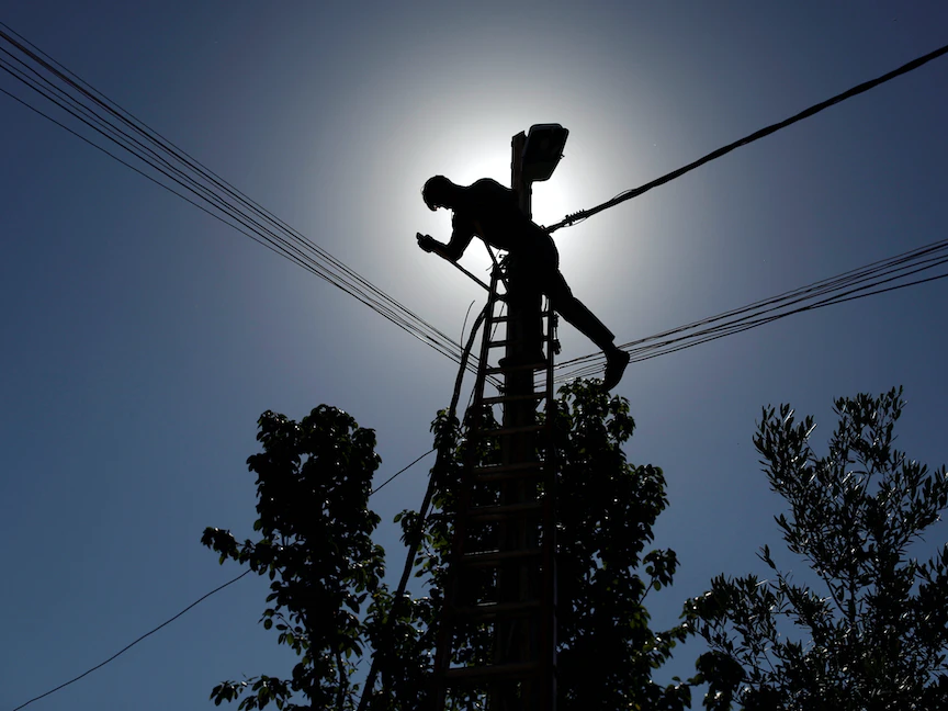 عامل عراقي يعمل على عمود كهرباء شرقي الموصل - REUTERS