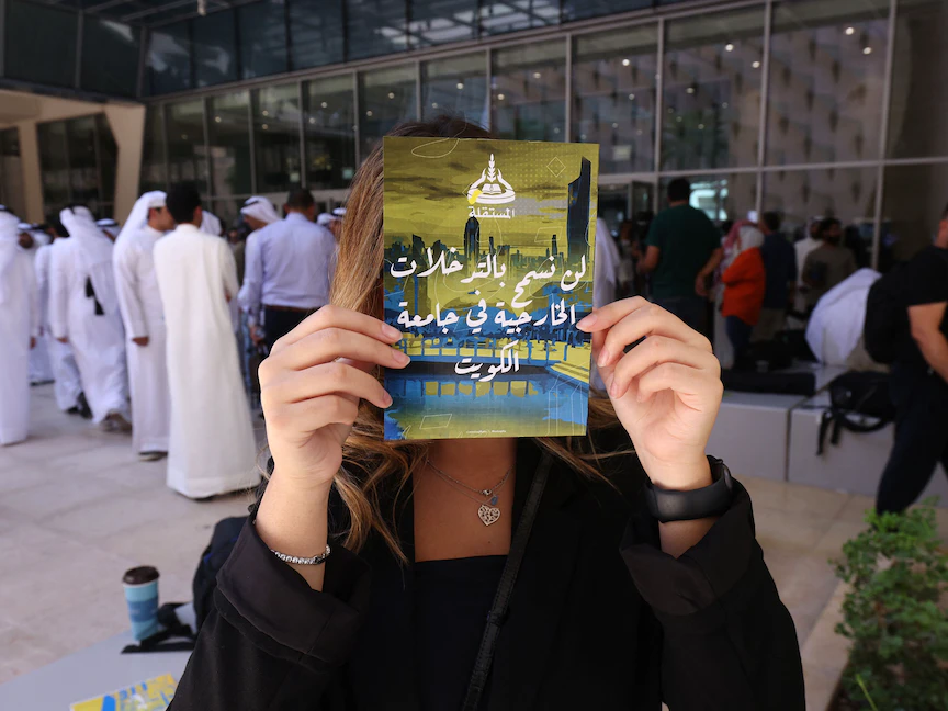 طالبة بجامعة الكويت ترفع لافتة احتجاجاً على قرار إدارة الجامعة بالفصل بين الطلاب في الشُعب الدراسية. 18 سبتمبر 2023 - AFP