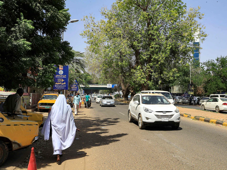 سيارات تمر بجانب المارة على طول شارع النيل المتاخم لنهر النيل الأزرق في العاصمة السودانية الخرطوم عقب عودة الحياة لطبيعتها بعد إعلان السلطات إفشال محاولة انقلابية- 21 سبتمبر 2021 - AFP