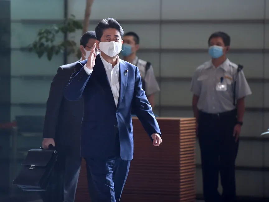 رئيس الوزراء الياباني شينزو آبي يحيي مستقبليه عند وصوله إلى مكتبه في طوكيو. - AFP