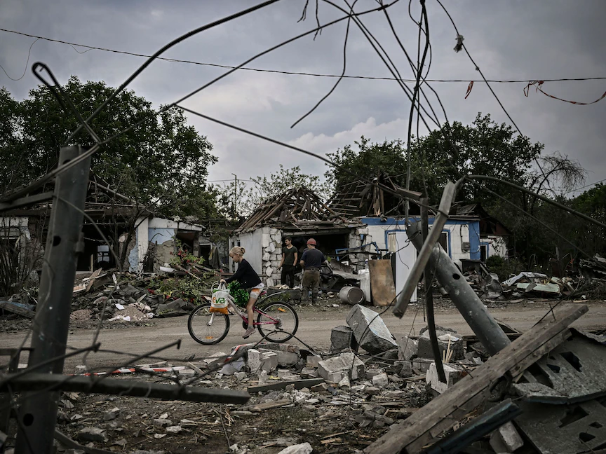 فتاة تركب دراجتها بين حطام المنازل المدمرة إثر هجوم على مدينة دوبروبيليا في منطقة دونباس بشرق أوكرانيا. 15 يونيو 2022 - AFP