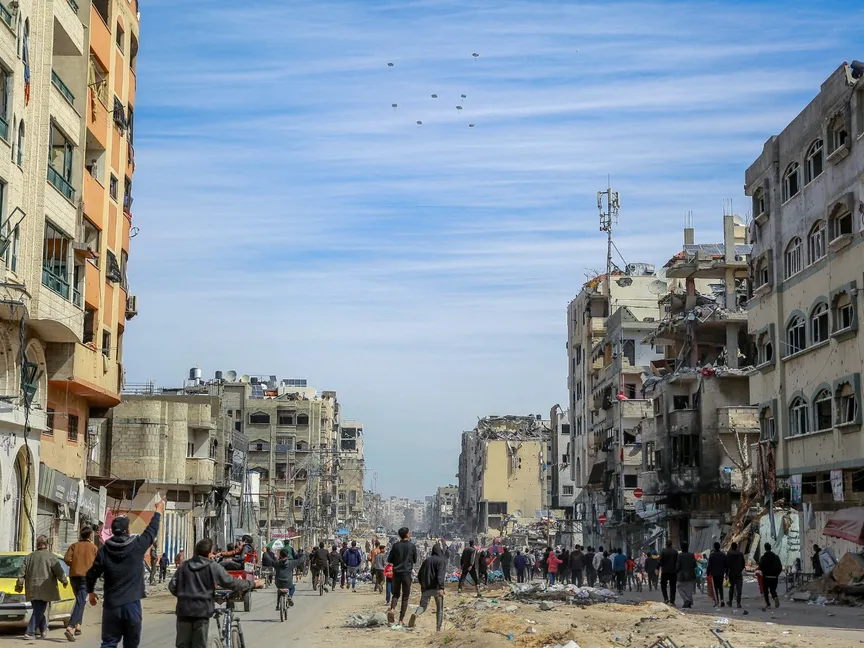 فلسطينيون يتجمعون في أحد الشوارع أثناء إسقاط المساعدات الإنسانية جواً في مدينة غزة، 1 مارس 2024 - AFP