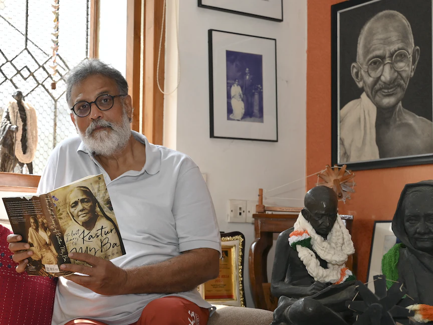 توشار غاندي نجل حفيد المهاتما غاندي يحمل كتاباً خلال مقابلة مع "فرانس برس" في منزله بمدينة مومباي. 25 يناير 2023 - AFP