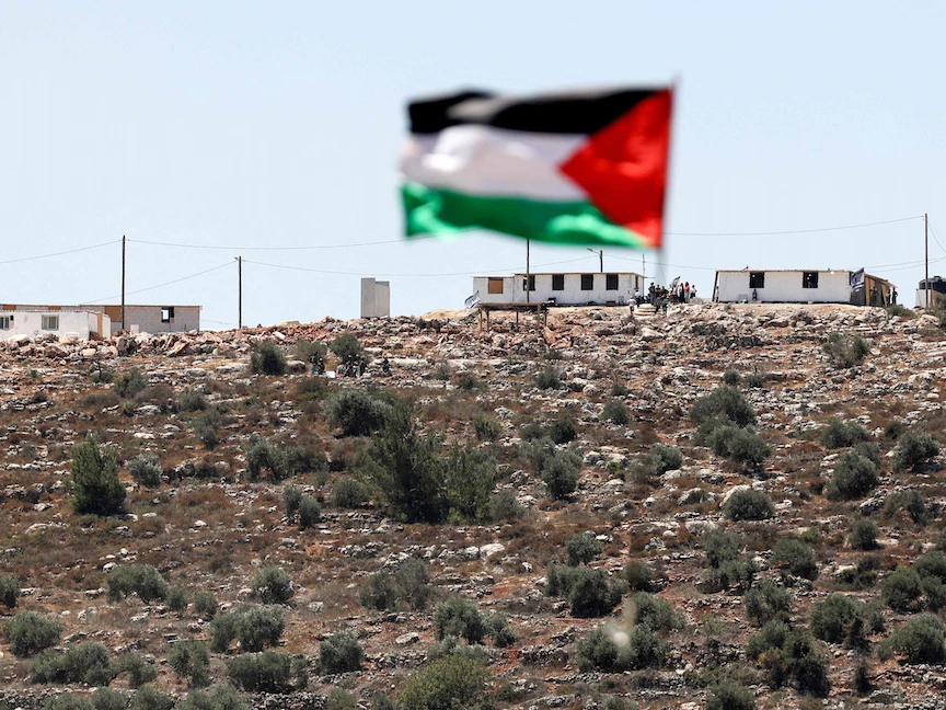 علم فلسطين يرفرف من أمام بؤرة استيطانية في قرية بيتا جنوب نابلس بالضفة الغربية- 18 يونيو 2021 - AFP