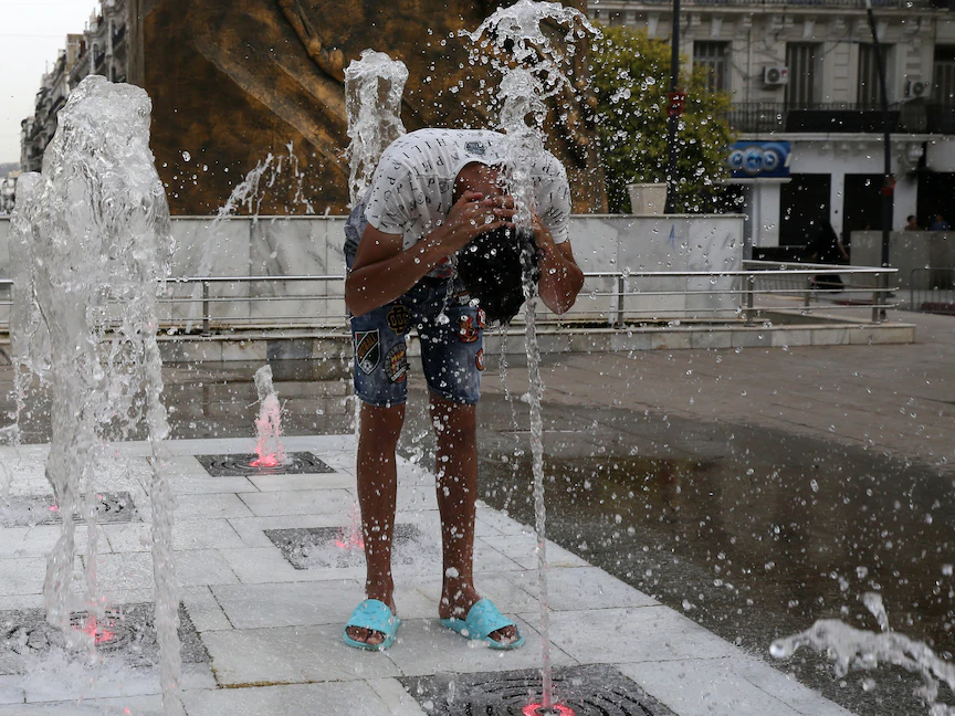 رجل يُبلل نفسه بالمياه وسط موجة حر وسط العاصمة الجزائر. 10 يوليو 2023 - AFP