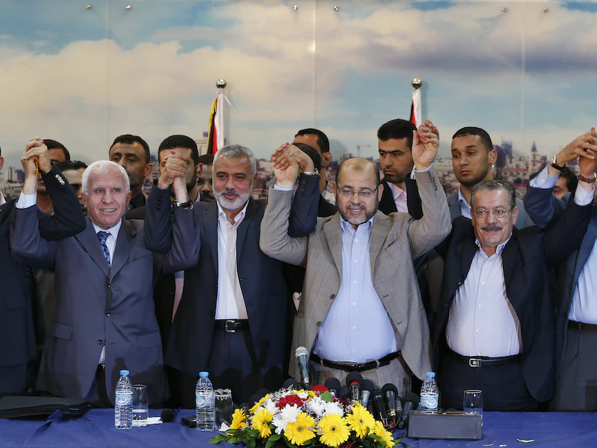 قيادات حركتي فتح وحماس يرفعون أيديهم بعد إعلان اتفاق المصالحة الفلسطينية في مدينة غزة - 23 إبريل 2014 - REUTERS