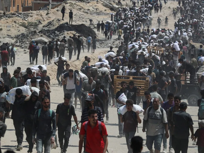 فلسطينيون يحملون مساعدات غذائية في بيت لاهيا بشمال قطاع غزة وسط أزمة جوع طاحنة. 27 يوليو 2025 - REUTERS