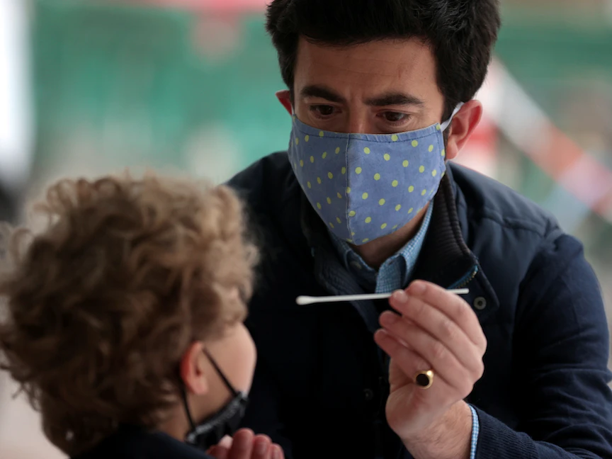 رجل يأخذ مسحة "بي سي آر" من ابنه في لندن - 14 مايو 2021 - REUTERS