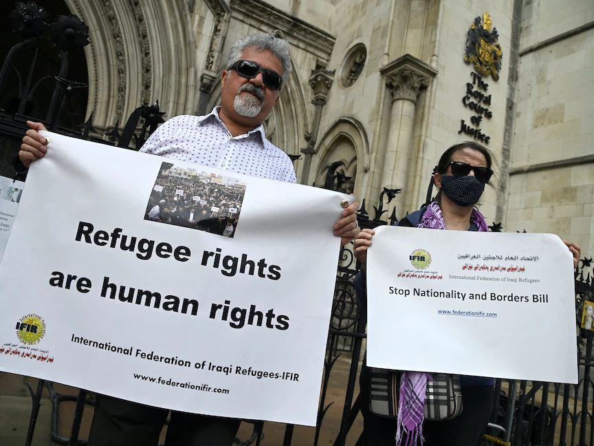 متظاهران يحتجان خارج محاكم العدل الملكية في لندن، أثناء النظر في قضية قانونية بشأن وقف الترحيل المزمع لطالبي اللجوء من بريطانيا إلى رواندا. 10 يونيو 2022 - REUTERS