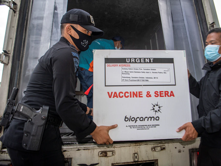 شرطيان إندونيسيان يحملان صندوقاً من لقاح سينوفاك الصيني المضاد لكورونا، لدى وصوله لإدارة الصحة المحلية في مقاطعة سومطرة الإندونيسية. 4 يناير 2021 - REUTERS
