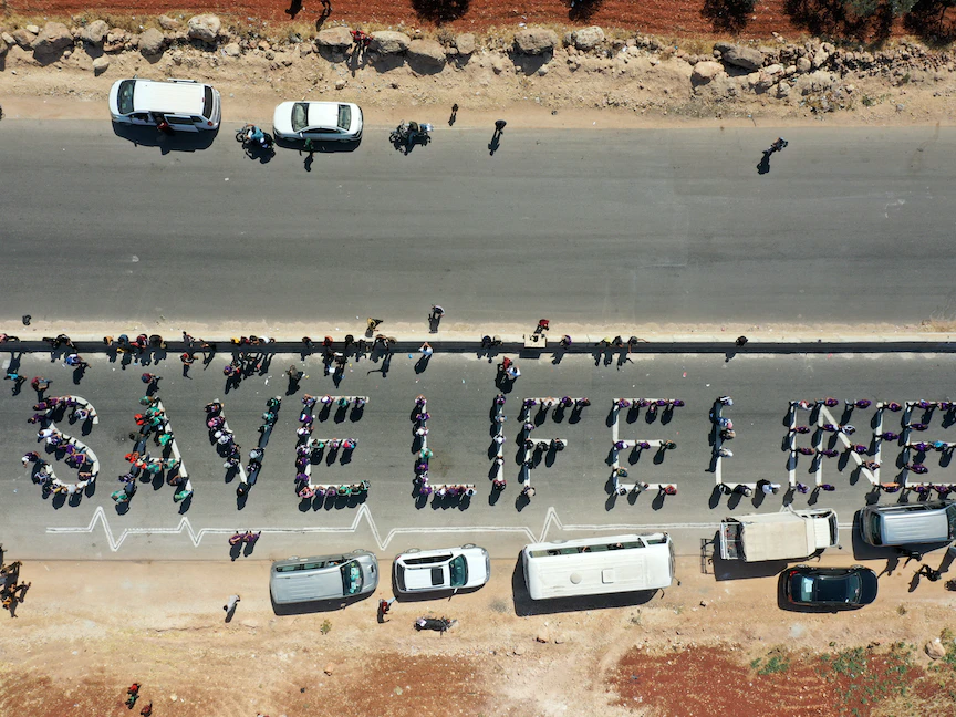 سلسلة بشرية من العاملين في المجتمع المدني والمساعدات الإنسانية في وقفة احتجاجية تدعو إلى الحفاظ على قرار أممي يسمح بمرور المساعدات الإنسانية إلى محافظة إدلب شمال غربي سوريا، 2 يوليو 2021 - AFP