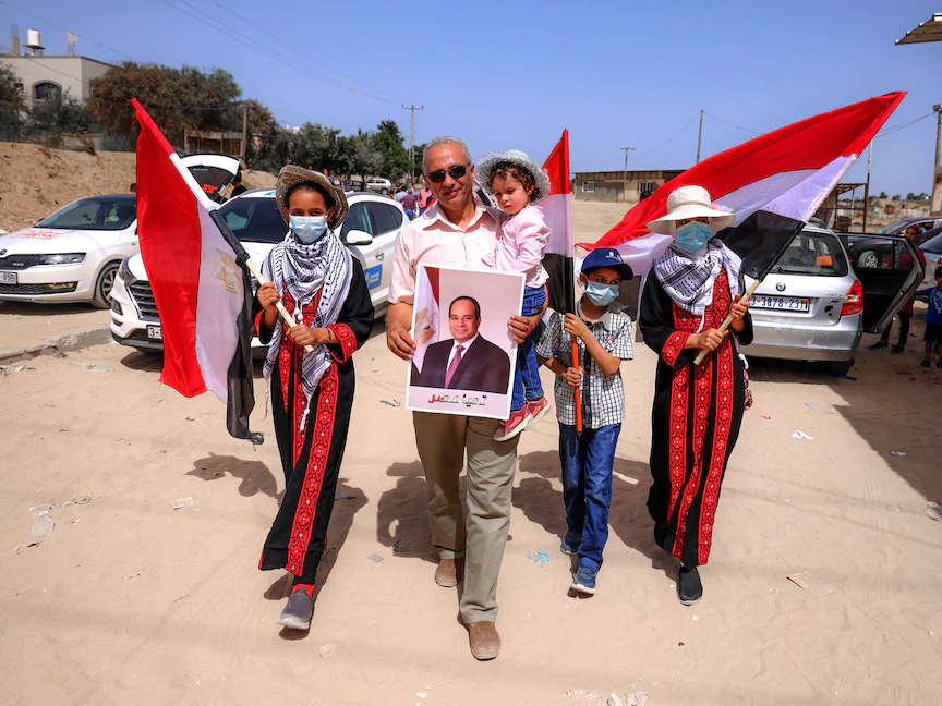 أسرة فلسطينية من قطاع غزة تحمل أعلام مصر وصورة للرئيس المصري عبد الفتاح السيسي خلال زيارة مدير المخابرات عباس كامل للقطاع - 31 مايو 2021 - AFP
