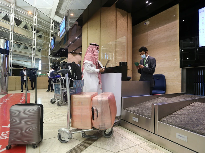 سعودي يعرض بطاقة تطعيمه عند مكتب تسجيل الوصول بمطار الملك خالد الدولي بعد أن رفعت المملكة حظر سفر مواطنيها - 16 مايو 2021 - - REUTERS