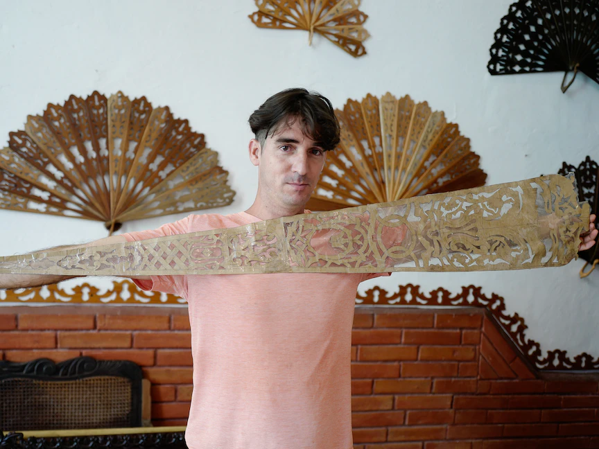 الحرفي الكوبي خوسيه ميجيل كادالسو يظهر نمطاً يستخدم كدليل لصنع مراوح يدوية خشبية في منزله في ترينيداد، كوبا. 20 يونيو 2023 - AFP