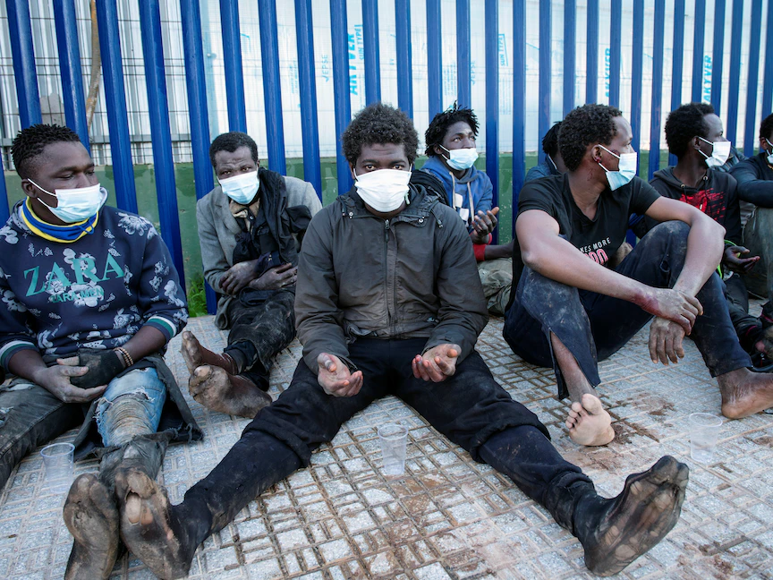 مهاجرون يجلسون خارج مركز المهاجرين المؤقتين عند عبور السياج في جيب مليلية بشمال إفريقيا، 19 يناير 2021 - REUTERS