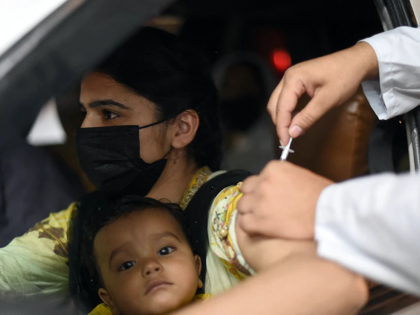 امرأة تحمل طفلها تحصل على لقاح "سينوفارم" في مركز تطعيم في مدينة لاهور الباكستانية - 10 يونيو 2021 - AFP