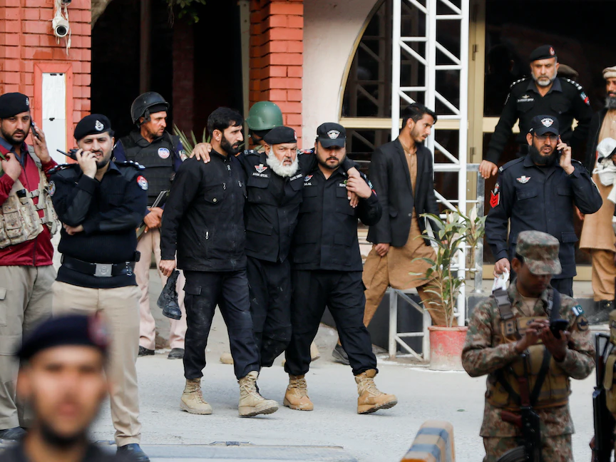 ضباط شرطة يساعدون ضابطاً مصاباً بعد انفجار انتحاري في مقر شرطة بالقرب من مسجد في مدينة بيشاور الباكستانية- 30 يناير 2023 - REUTERS