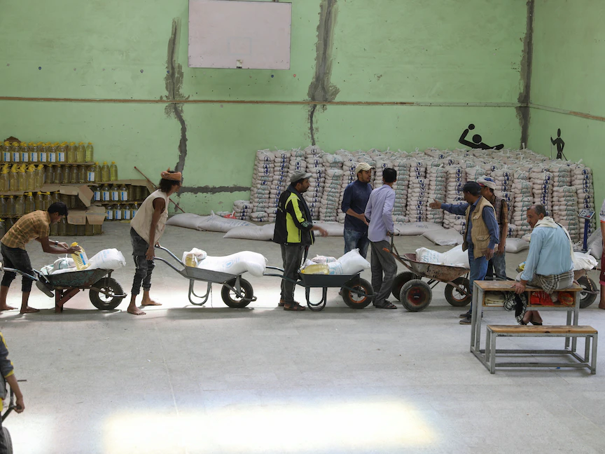 عمال ينقلون مساعدات غذائية للمستفيدين من برنامج الغذاء العالمي في مركز توزيع في صنعاء، اليمن. 18 يوليو 2023 - REUTERS