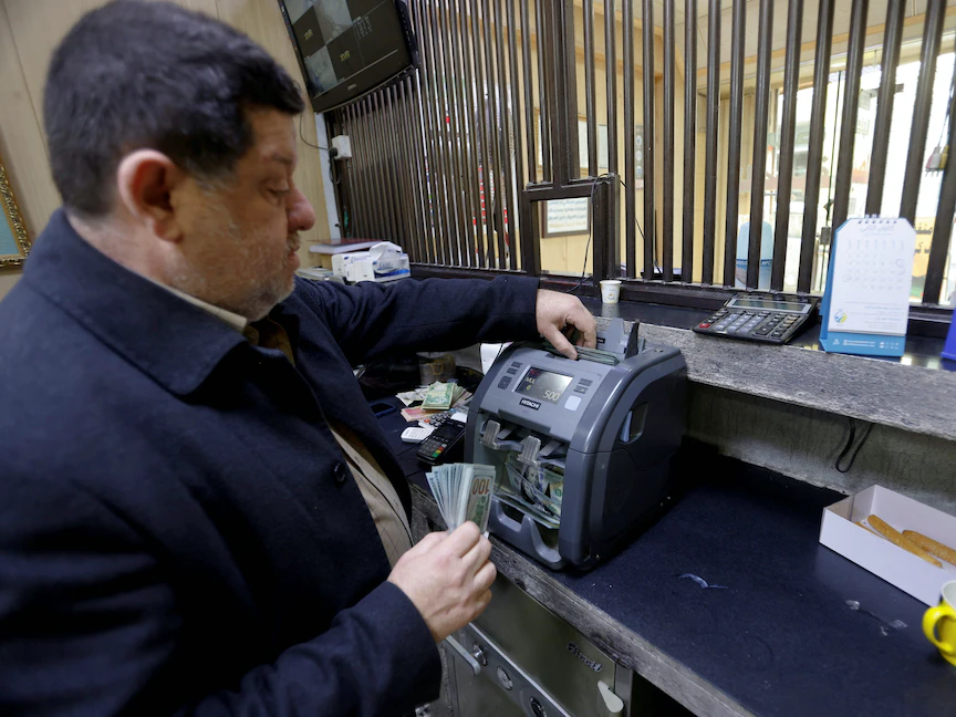مصرفي يعد الدولارات في محل للصرافة في العاصمة بغداد. 23 يناير 2023 - REUTERS