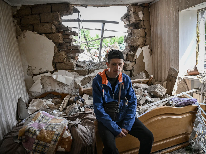 الأوكراني سيرجي تاراشوك يجلس على سرير في منزله الذي دمرته هجمة صاروخية في مدينة سلوفيانسك شرقي أوكرانيا – 1 يونيو 2022 - AFP