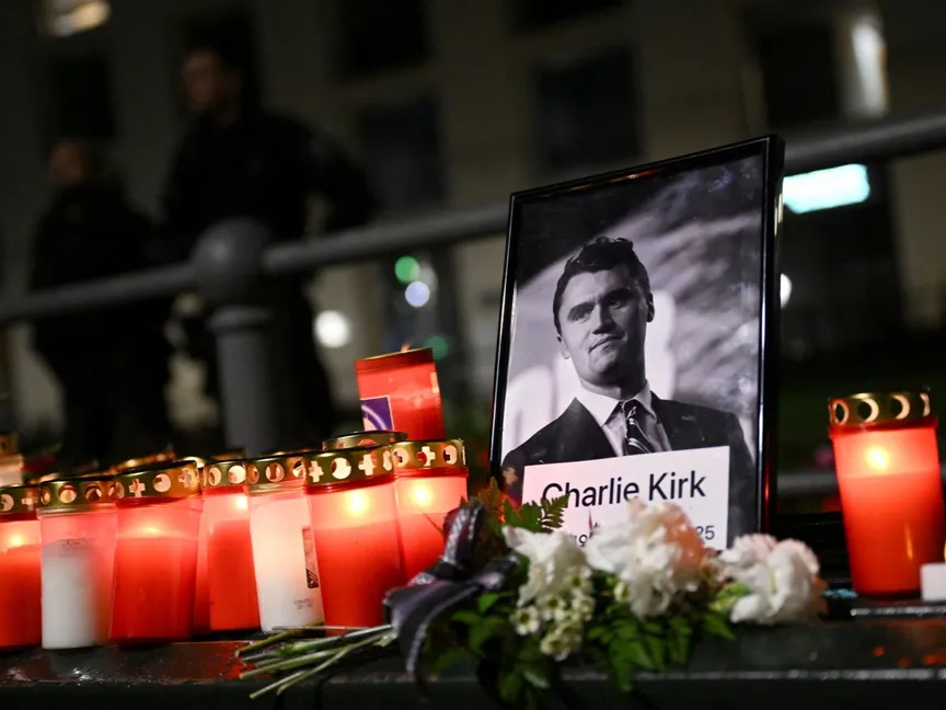 ورود وشموع بجانب صورة الناشط الأميركي الراحل تشارلي كيرك خلال وقفة احتجاجية أمام سفارة الولايات المتحدة في برلين. 11 سبتمبر 2025 - REUTERS