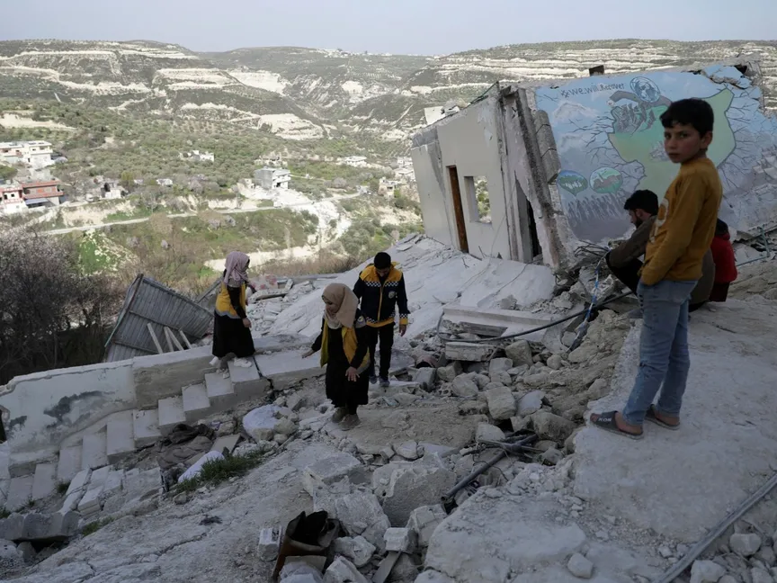 متطوعون يقفون على أنقاض مبنى تضرر جرّاء الزلزال المدمر الذي ضرب سوريا وتركيا في قرية الملند بمحافظة إدلب في سوريا. 5 مارس 2023 - REUTERS