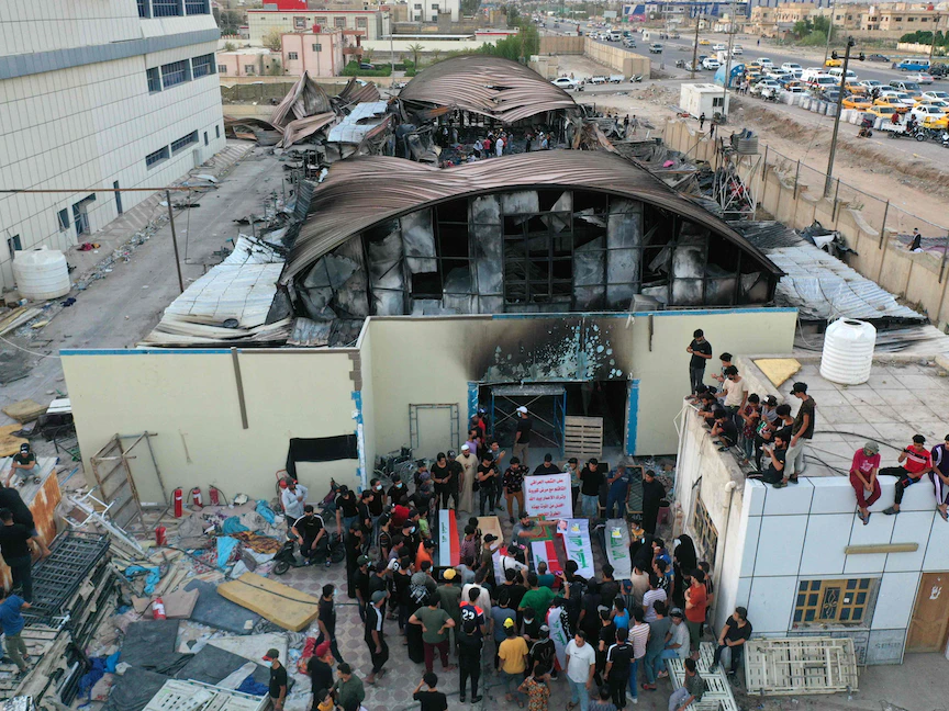 عراقيون يضعون توابيتاً رمزية أمام جناح عزل فيروس كورونا الذي دمرته النيران في مستشفى الحسين بمدينة الناصرية جنوب العراق، 15 يوليو 2021 - AFP