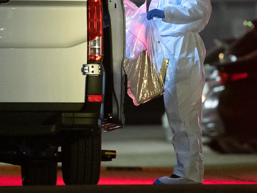 متخصص في الطب الشرعي يحضر كيساً بلاستيكياً إلى شاحنة صغيرة بالقرب من موقع الانفجار في مكاتب "ليدل" ينيكارسولم جنوب غربي ألمانيا- 17 فبراير 2021 - AFP