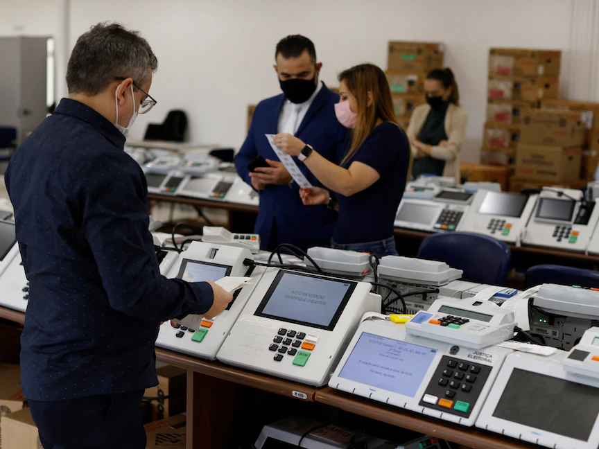 موظفون في المحكمة الانتخابية يتحققون من أداء أجهزة التصويت الإلكتروني في مدينة كوريتيبا البرازيلية- 24 يونيو 2022 - REUTERS