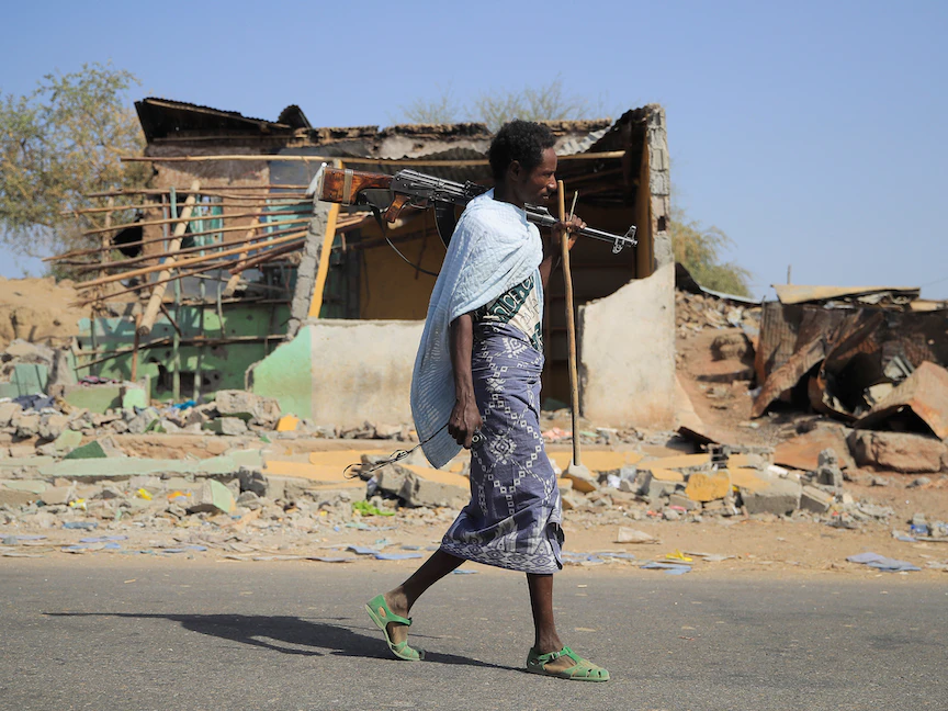عنصر مسلح يسير بجوار منزل دمر في القتال بين الجيش الإثيوبي وقوات جبهة تحرير تيجراي في بلدة كاساجيتا بمنطقة عفار في إثيوبيا. 25 فبراير 2022 - REUTERS