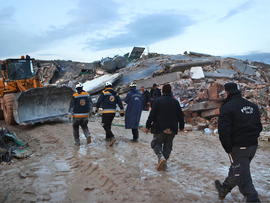 عمال إنقاذ يسيرون بجوار مبنى منهار في بلدة سرمدا بمحافظة إدلب شمال غربي سوريا. 6 فبراير 2023 - AFP