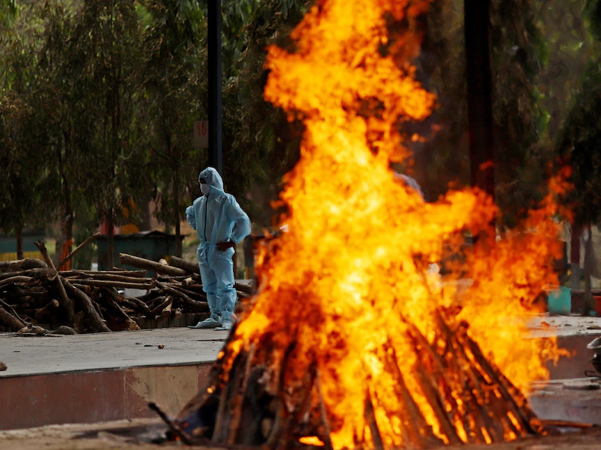 عامل قرب محرقة لجثث متوفين بفيروس كورونا في ضواحي نيودلهي، 23 أبريل 2021 - Bloomberg