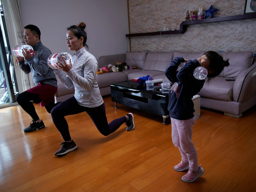 أسرة تمارس الرياضة باستخدام زجاجات المياه أثناء مشاهدة دروس لياقة بدنية عبر الإنترنت في منزلهم بشنغهاي، الصين- 25 فبراير 2020 - REUTERS
