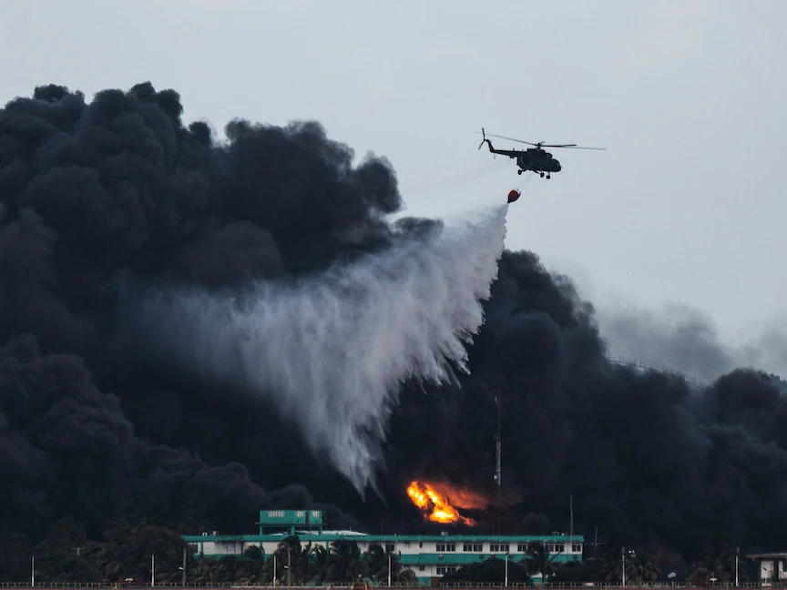 طائرة هليكوبتر تابعة لرجال الإطفاء تلقي المياه على حريق هائل في مستودع وقود في ماتانزاس في كوبا - AFP