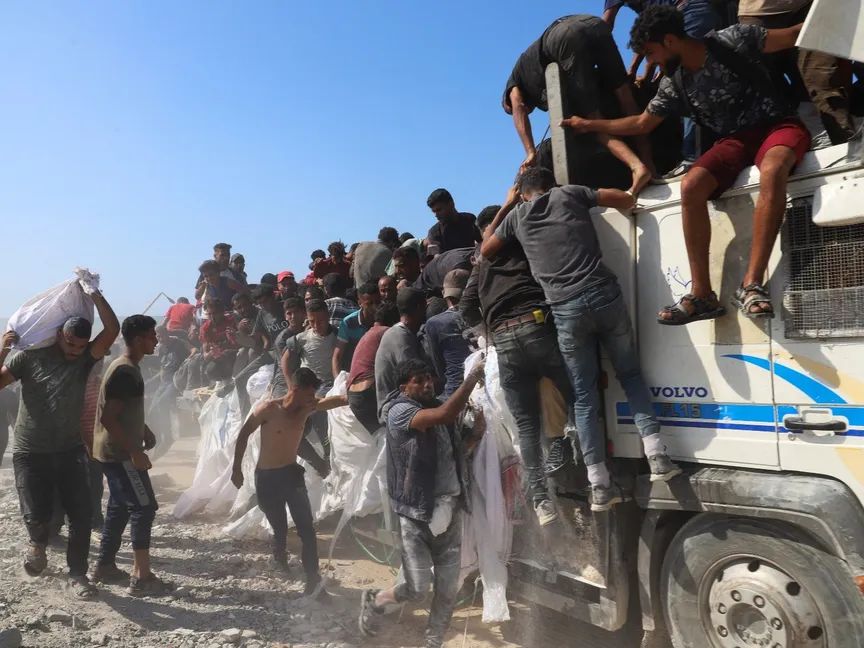 فلسطيني يحمل مساعدات دخلت غزة بينما يعتلي آخرون شاحنة في محاولة للحصول على مواد غذائية، بيت لاهيا شمال قطاع غزة. 3 أغسطس 2025 - Reuters