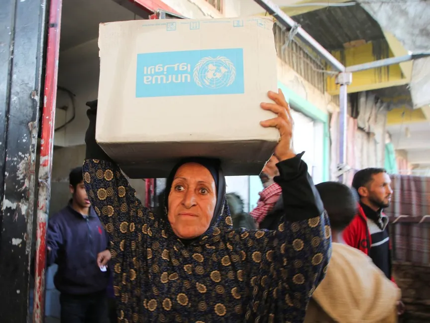 سيدة فلسطينية تحمل صندوق مساعدات وزعته وكالة الأمم المتحدة لغوث وتشغيل اللاجئين الفلسطينيين (الأونروا) في خان يونس جنوبي قطاع غزة. 21 يناير 2025 - REUTERS