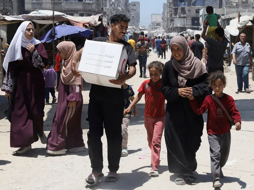 عائلة فلسطينية تحمل صندوقاً للمساعدات الإنسانية في بيت لاهيا بشمال قطاع غزة. 26 يونيو 2025 - REUTERS