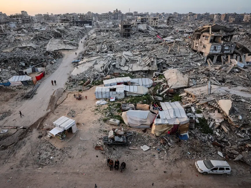 فلسطينيون وسط أنقاض المباني السكنية التي دمرتها الحرب الإسرائيلية في مدينة غزة. 18 فبراير 2026 - Reuters