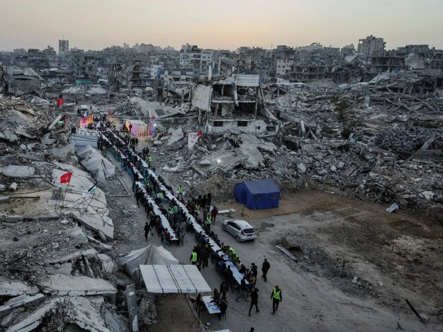 فلسطينيون يجتمعون لتناول إفطار اليوم الأول من شهر رمضان بالقرب من أنقاض المباني السكنية التي دمرتها الحرب الإسرائيلية في مدينة غزة. 18 فبراير 2026 - REUTERS