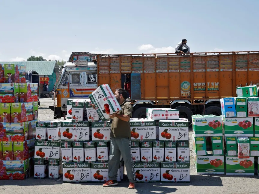 مزارع يحمل صندوقاً من التفاح الطازج في سوق الفاكهة بينما كانت شاحنة محملة بالتفاح على طول الطريق السريع الوطني جامو-سريناجار في كشمير الهندية. 10 سبتمبر 2025 - reuters