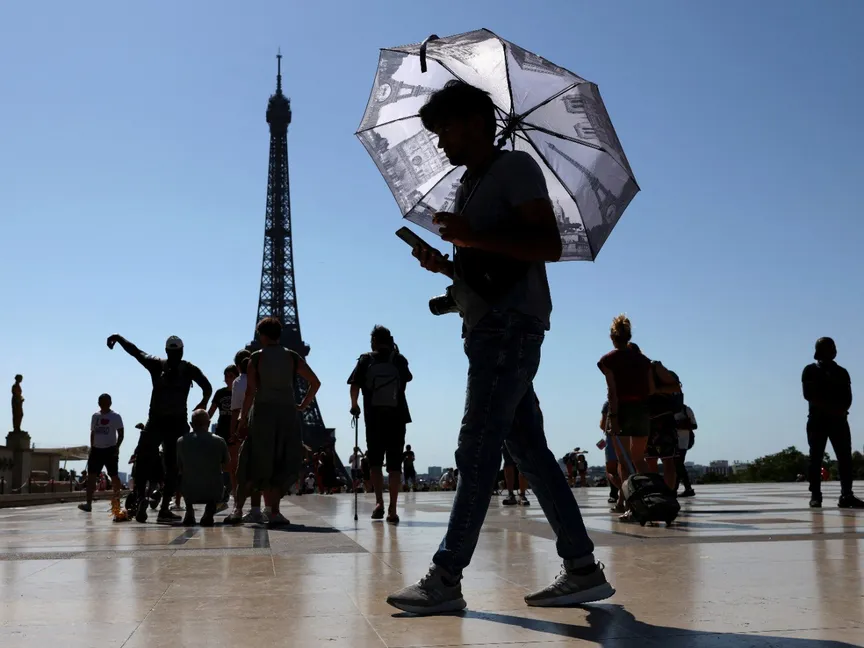 سائح يحمل مظلة في ساحة تروكاديرو بجوار برج إيفل وسط موجة من الحر الشديد في باريس. 1 يوليو 2025 - Reuters