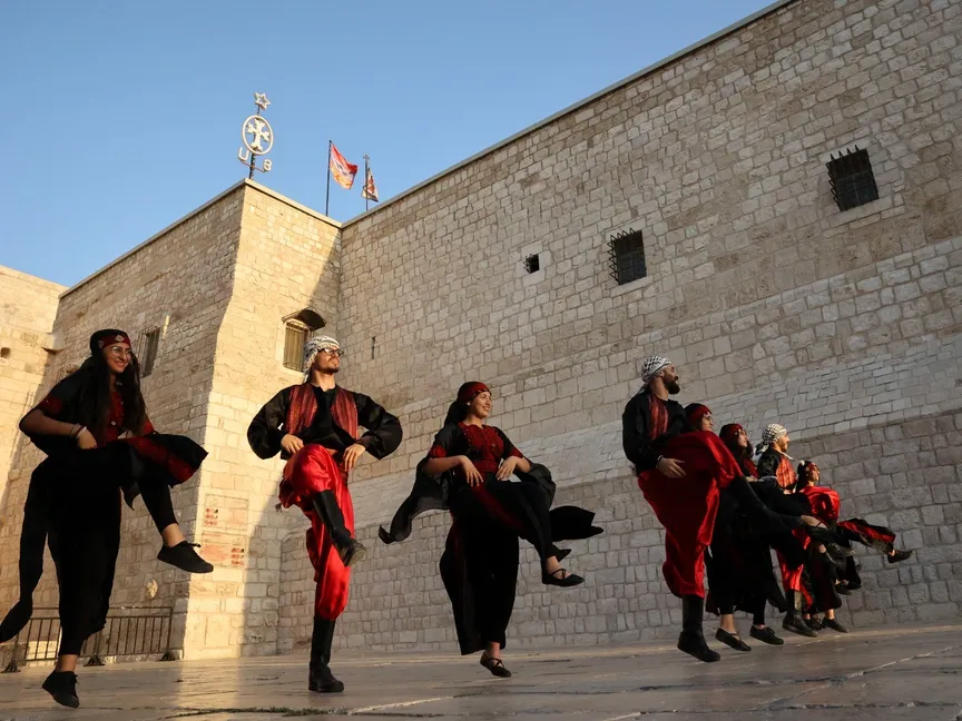 فرقة فلسطينية تؤدي الدبكة أمام كنيسة المهد. الضفة الغربية، فلسطين. 26 أغسطس 2021. - AFP