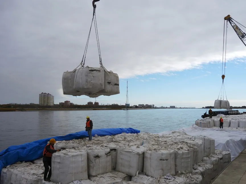 عمال يقفون قرب رافعة أثناء تفريغ شحنة فول صويا روسية في ميناء هيهي بمقاطعة هيلونججيانج شمال شرق الصين. 10 أكتوبر 2018 - REUTERS